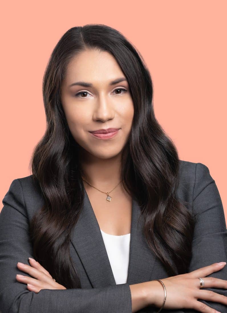 Jacquelyn Silva attorney long brunette hair wearing gray blazer, white top, chest up portrait