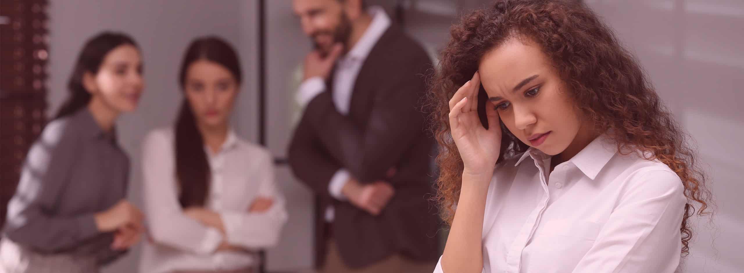 Latino woman being gossiped about by work colleagues