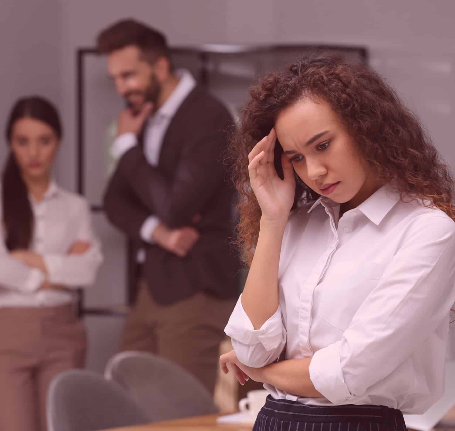 Latino woman being gossiped about by work colleagues