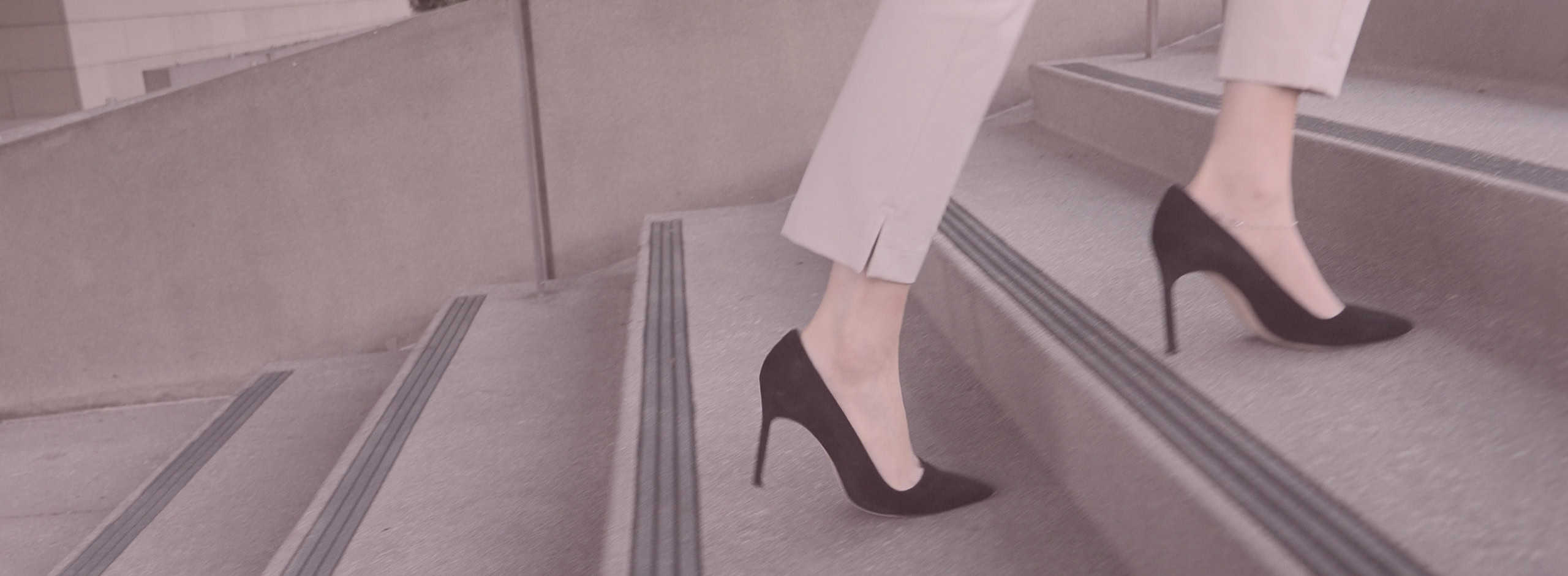 Woman in high heels walking up outside stairs, visible knees down.