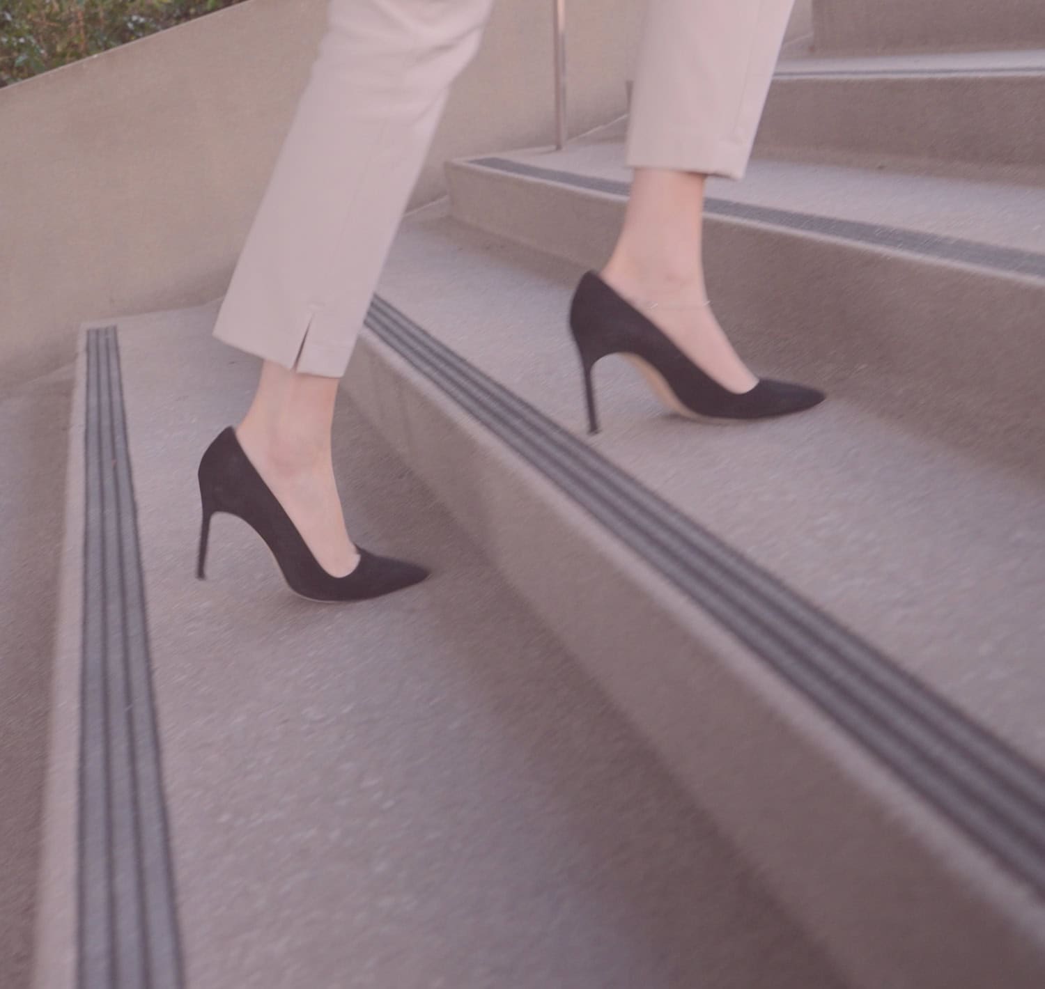 Woman in high heels walking up outside stairs, visible knees down.